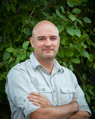 Photo of a man standing in front of a tree